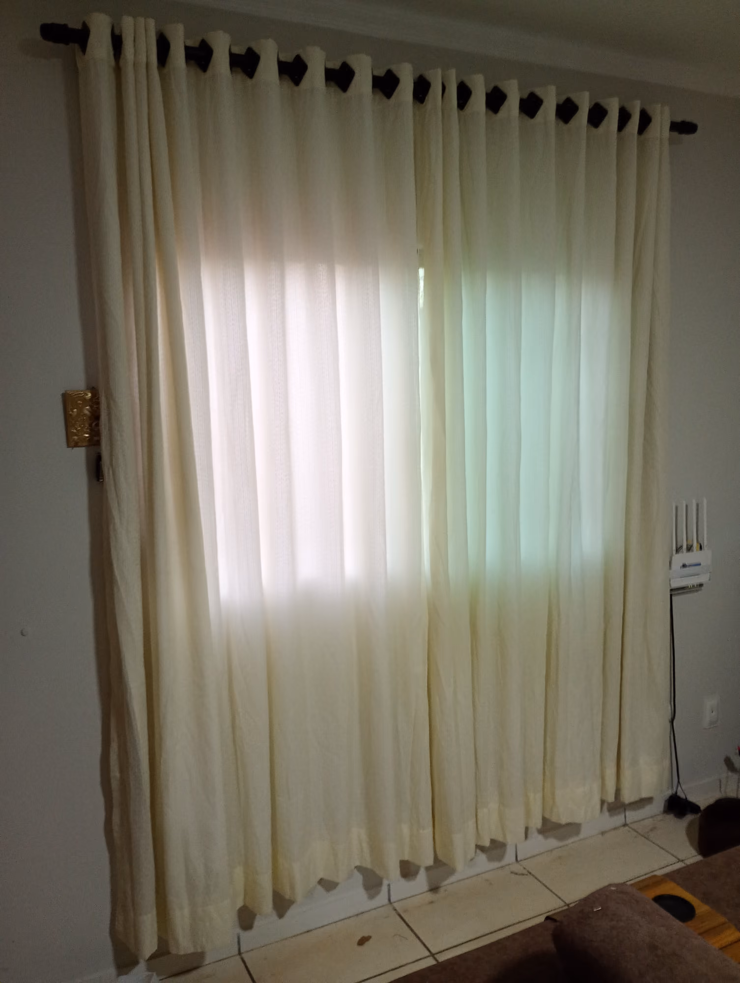 Cortina de tecido cru com varão instalada em janela de sala de estar em Campo Grande - MS
