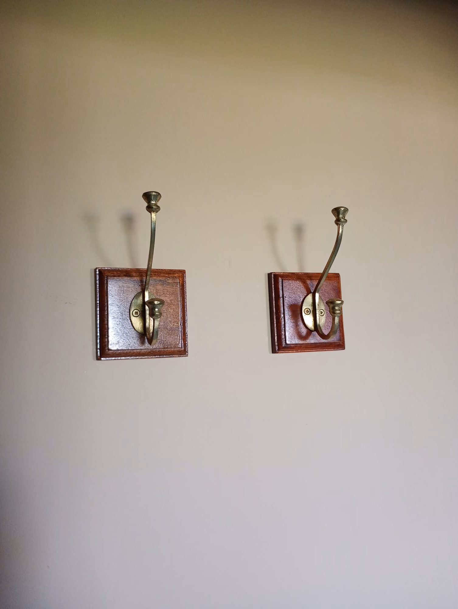 Par de cabides de parede em madeira fixados em parede de quarto