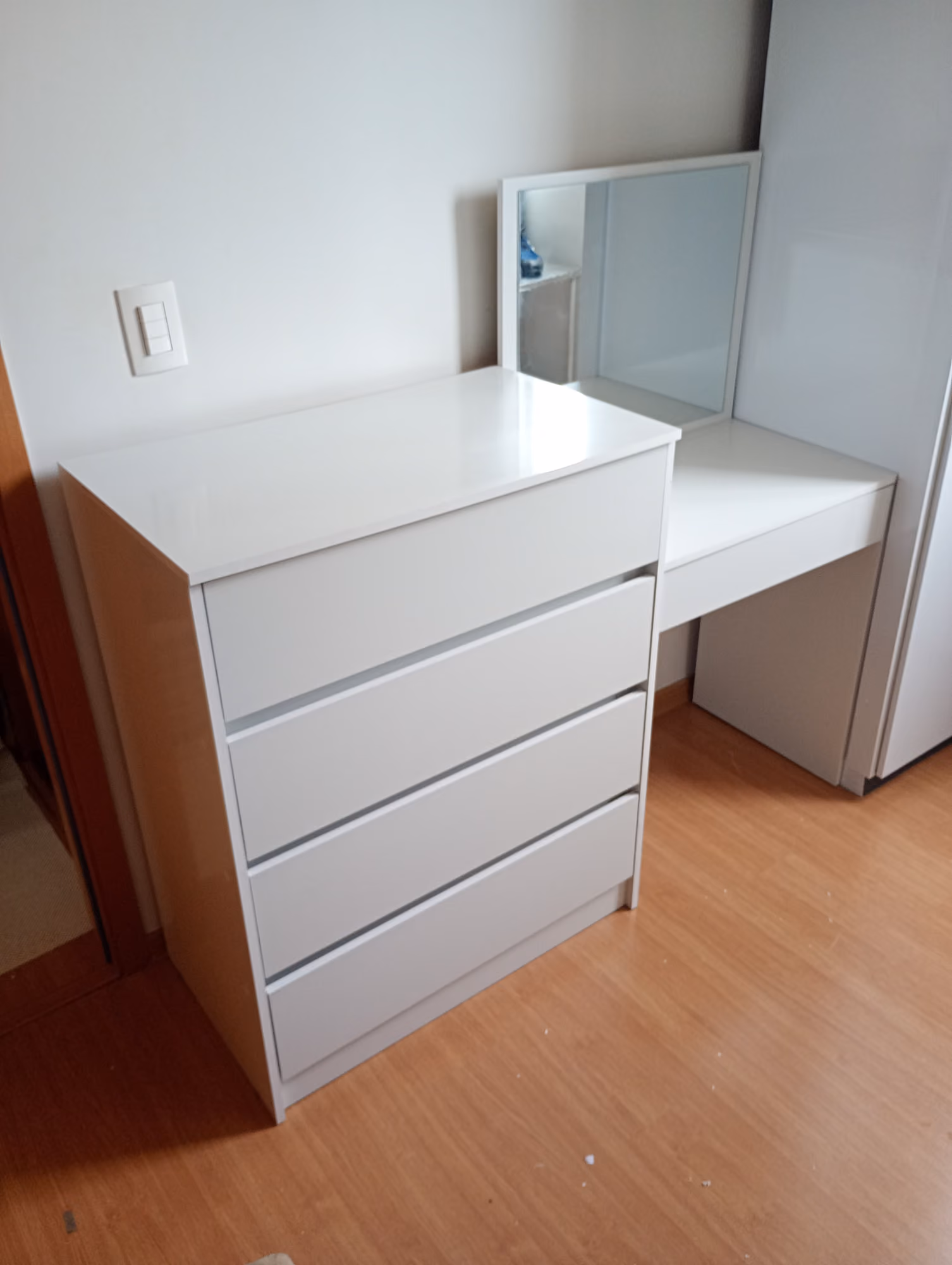 Cômoda branca de 4 gavetas e penteadeira com espelho montadas em quarto