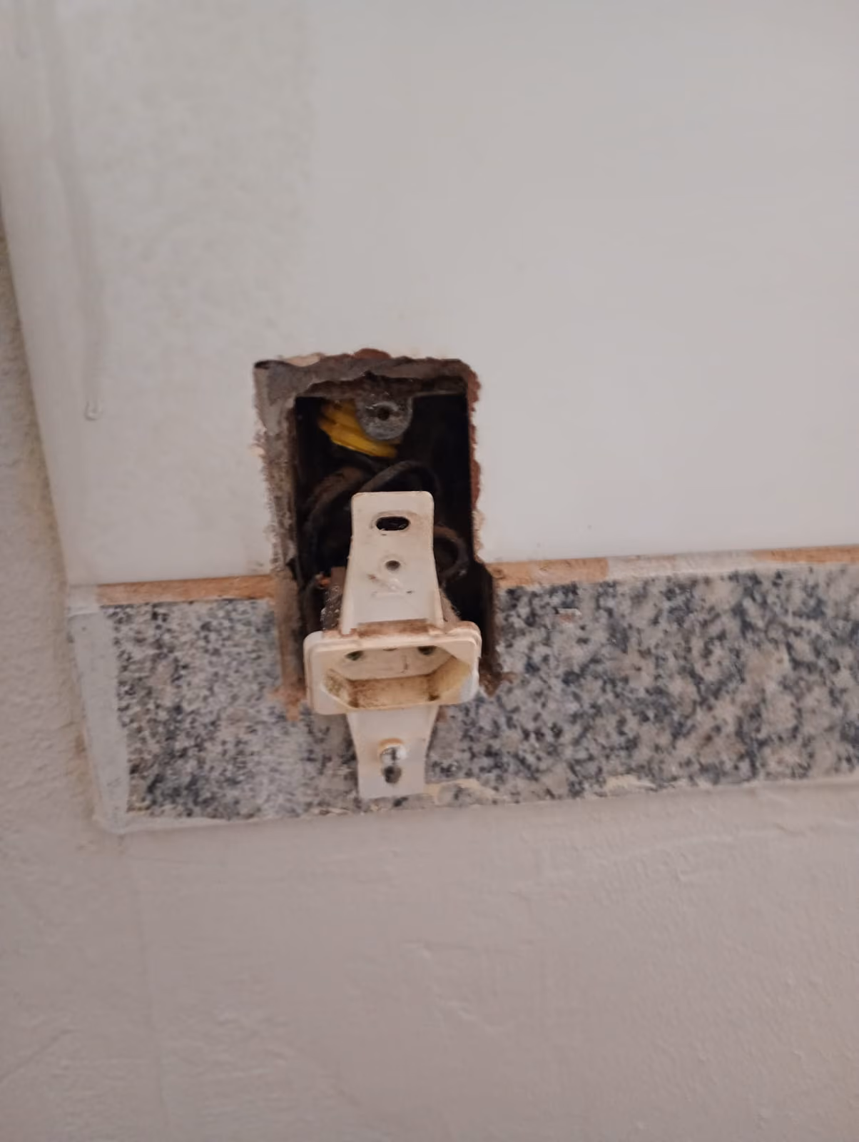 Caixa de tomada antiga aberta na parede antes da troca do ponto elétrico
