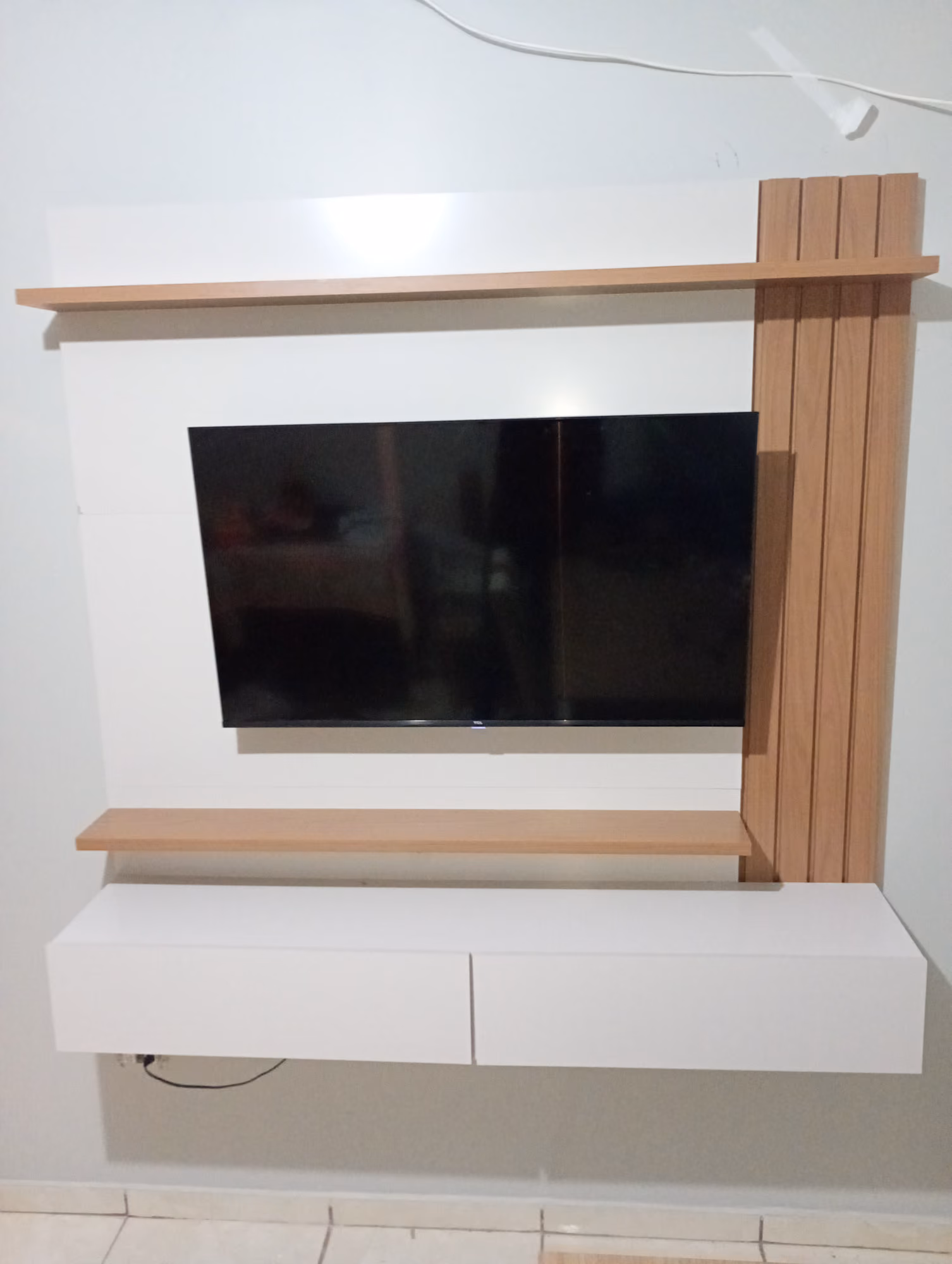 Painel de TV com ripado de madeira e televisor instalados em sala em Campo Grande - MS