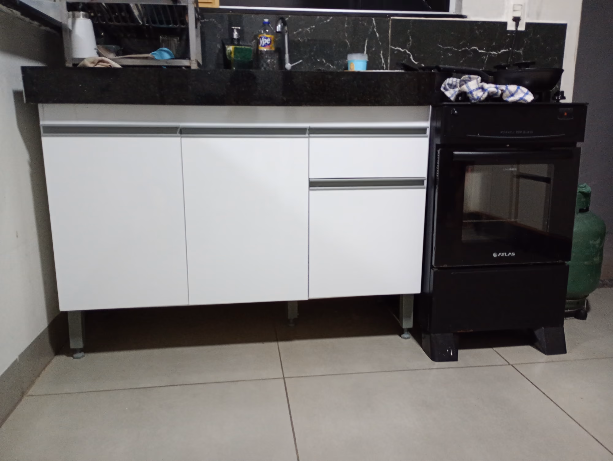 Gabinete de pia branco montado sob bancada de granito em cozinha residencial