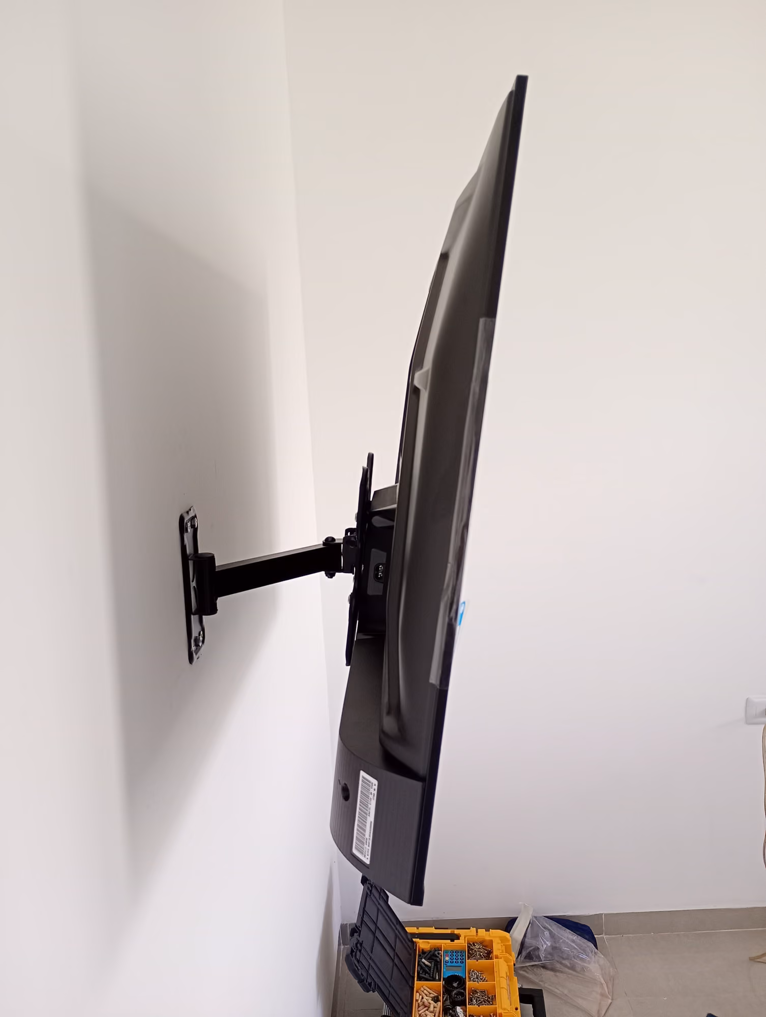 Televisor fixado em suporte articulado de parede, visto de perfil após a instalação