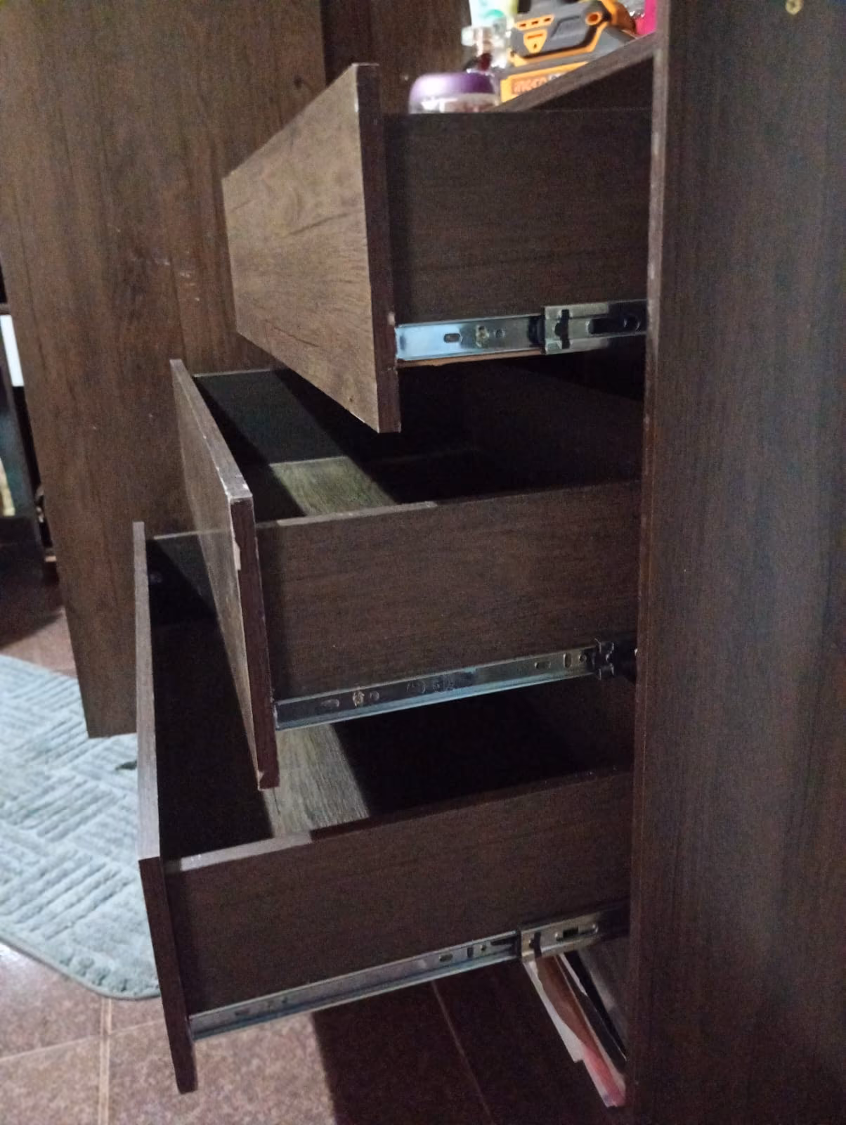 Troca de corrediças em gavetas de guarda-roupa de madeira escura em quarto