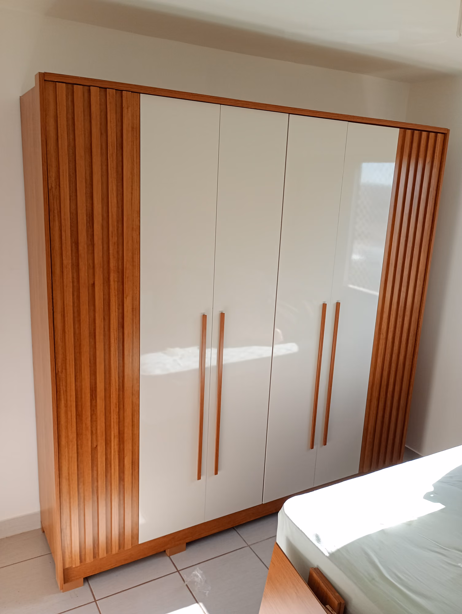Guarda-roupa de 4 portas branco com laterais ripadas em madeira montado em quarto