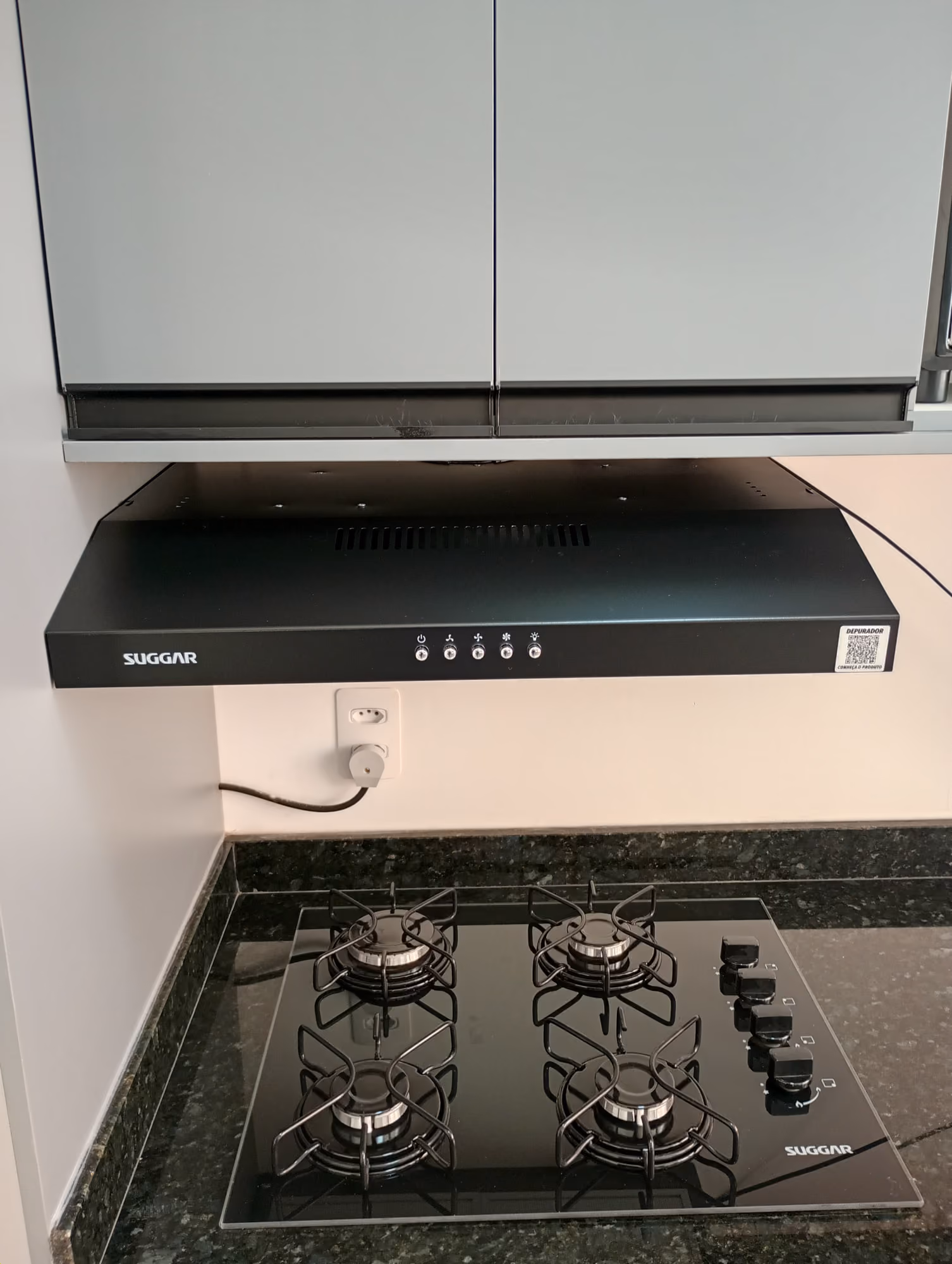 Depurador de ar Suggar instalado sob armário aéreo, acima de cooktop de 4 bocas