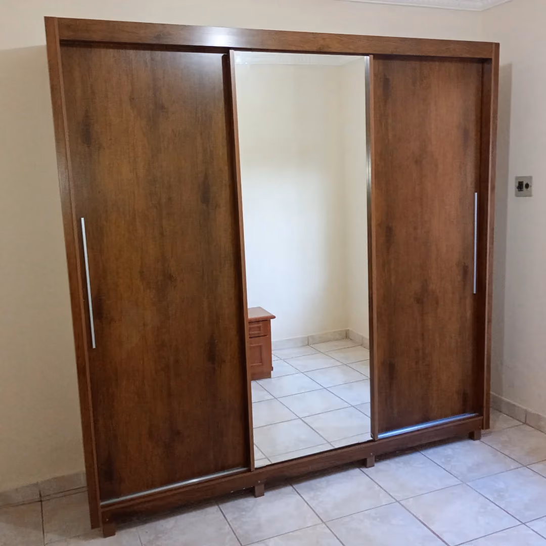 Guarda-roupa de 3 portas de correr em madeira escura com espelho central montado em quarto